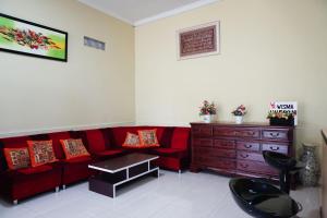 a living room with a red couch and a wooden dresser at OYO Life 3003 Wisma Handayani Syariah in Yogyakarta