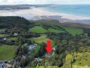 eine Luftansicht eines Hauses mit einem roten Pfeil in der Unterkunft Coastal Cottage with Stunning Views Pass the Keys in Llanddona