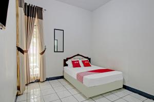 a bedroom with a bed with red pillows on it at OYO 90543 An-nur Guest House Syariah in Kuningan