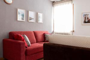 a living room with a red couch and a window at Chalet Ginepro in Santa Caterina Valfurva