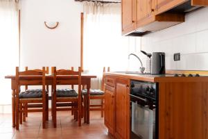 una cucina con armadi in legno, tavolo e sedie di Chalet Ginepro a Santa Caterina Valfurva