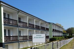 a white building with a sign in front of it at Pension Dünenhaus in Zempin