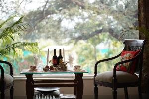 a table with bottles of wine and two chairs in front of a window at Castle Oodeypore A Boutique stay Udaipur in Udaipur