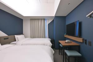 a hotel room with two beds and a tv at Prince Smart Inn Hakata in Fukuoka