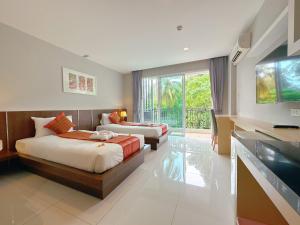 a bedroom with two beds and a tv and a couch at Ahad Suite Aonang in Ban Khlong Haeng