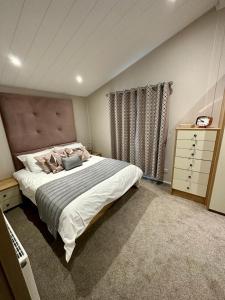 a bedroom with a large bed and a dresser at Luxury 3 bedroom Maple View Lodge, Newquay, Cornwall in Newquay