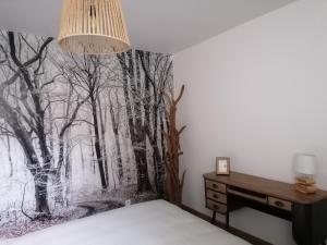 ein Schlafzimmer mit einem Wandbild von Bäumen in der Unterkunft La maison Saint-Gervais in Falaise