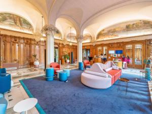 Cette grande chambre comprend un canapé et des chaises. dans l'établissement Mercure Lyon Centre Château Perrache, à Lyon