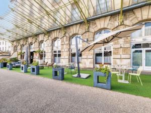 a building with tables and chairs and a glass ceiling at Mercure Lyon Centre Château Perrache in Lyon