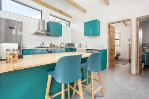 Mountain and Sea Cottage في هيرمانوس: مطبخ مع خزائن خضراء وكراسي زرقاء
