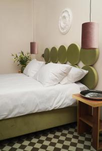 a bedroom with a bed with a green headboard and a table at Hotel Pietryna in Łódź