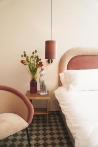 a bedroom with a bed and a table with a vase of flowers at Hotel Pietryna in Łódź