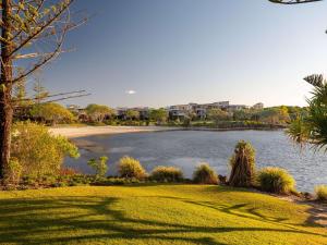 a park with a body of water with buildings in the background at The Sebel Twin Waters in Twin Waters