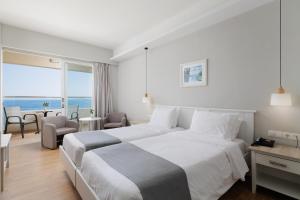 a hotel room with a bed and a view of the ocean at Elea Beach Hotel in Dassia