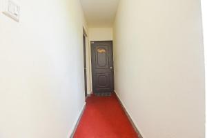 a hallway with a black door and a red carpet at FabHotel IRAA Resort With Pool in Baga