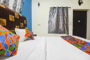 um quarto com uma cama branca e almofadas coloridas em FabHotel IRAA Resort With Pool em Baga