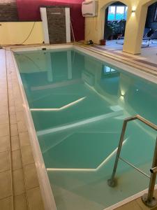 a swimming pool with green water in a building at HotelPension Weberhof in Ebersberg