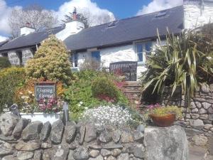 un jardín frente a una casa con una pared de piedra en Traditional stone cottage with sea views in Snowdonia National Park, en Brynkir