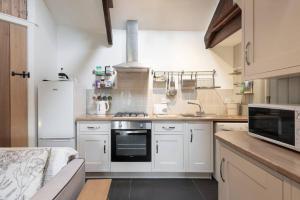 cocina con armarios blancos y fogones en Traditional stone cottage with sea views in Snowdonia National Park, en Brynkir