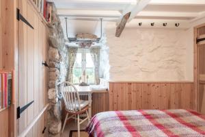 a bedroom with a bed and a chair in a room at Traditional stone cottage with sea views in Snowdonia National Park in Brynkir
