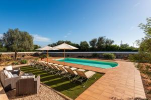 una piscina con sillas y sombrilla en Villa Son Prats, en Cala Santandria