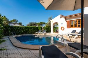 Una piscina con sillas y una sombrilla al lado de una casa. en Villa Thea, en Cala Blanca