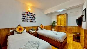 a hotel room with two beds and a tv at Darjeeling Hillside Inn in Darjeeling