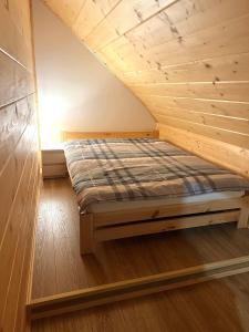 a bed in a room with a wooden ceiling at Highlander - drewniany dom w Beskidach in Kamesznica