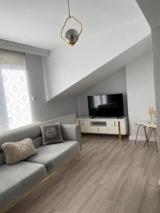 uma sala de estar com um sofá e uma televisão de ecrã plano em Şehir Merkezinde,Dublex apartman em Çanakkale