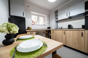 a kitchen with a wooden table with white plates on it at Fortuna Apartments in Baia Mare