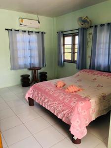 a bedroom with a pink bed with a pink blanket at Baan Termsuk in Khao Kho