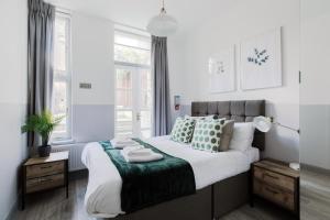 een slaapkamer met een groot bed met groene en witte kussens bij Modern Kensington Apartments in Londen
