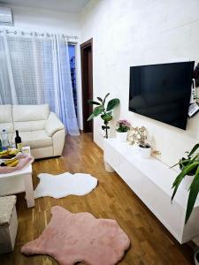 uma sala de estar com um sofá branco e uma televisão de ecrã plano em Boutique apartman Dora Angel em Budva