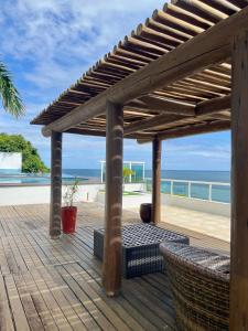 eine Holzterrasse mit einer Pergola und dem Strand in der Unterkunft Apartamento-Cobertura de Luxo Vista Mar em Salvador in Salvador