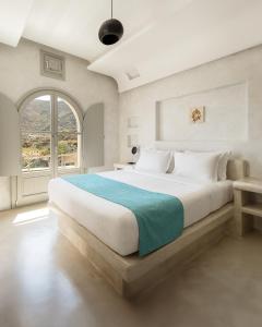 a bedroom with a large bed with a large window at Danae Suites Santorini in Oia +88 photos