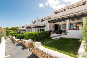 a large white house with a stone fence at Apartamento Arenal Jardin in Arenal d'en Castell