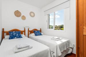 two beds in a room with a window at Apartamento Arenal Jardin in Arenal d'en Castell +29 photos