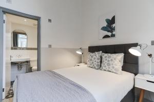 een slaapkamer met een bed, een wastafel en een spiegel bij Modern Kensington Apartments in Londen