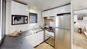 a kitchen with white cabinets and a stainless steel refrigerator at Camping Officiel Siblu le Montourey in Fréjus