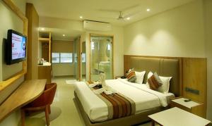 a hotel room with a bed and a television at FabHotel Prime Surya in Jabalpur