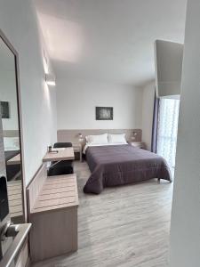 1 dormitorio con cama, mesa y espejo en Affittacamere In Centro en Tortolì