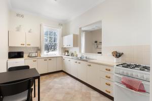 a kitchen with white cabinets and a table and a stove at TWO BEDROOM Apartment in Sydney