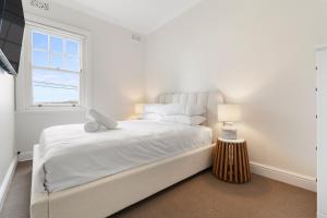 a white bedroom with a bed with a laptop on it at Heritage Terrace with Harbour Glimpses for 6 in Sydney +17 photos