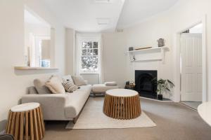 a living room with a couch and two wooden stools at Heritage Terrace with Harbour Glimpses for 6 in Sydney