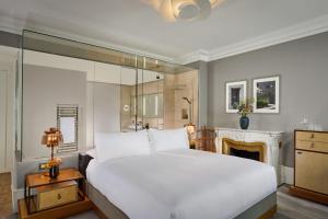 ein Schlafzimmer mit einem großen weißen Bett und einem Kamin in der Unterkunft The Ritz-Carlton Hotel de la Paix, Geneva in Genf