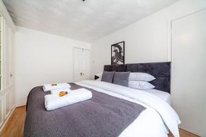 a bedroom with a large white bed with towels on it at Stunning 3 Bed House with Private Garden, Woolwich in London