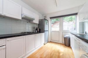 a kitchen with white cabinets and a large window at Stunning 3 Bed House with Private Garden, Woolwich in London