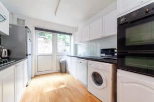 a white kitchen with a washer and dryer in it at Stunning 3 Bed House with Private Garden, Woolwich in London