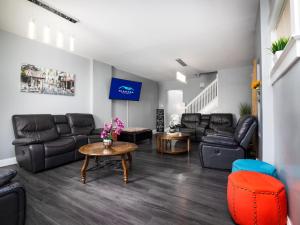 a living room with black leather furniture and a table at The Wheel of Fortune Duplex- 8BR Free Parking, Minutes From Falls & Casino in Niagara Falls