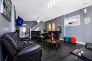 a living room with leather furniture and a table at The Wheel of Fortune Duplex- 8BR Free Parking, Minutes From Falls & Casino in Niagara Falls